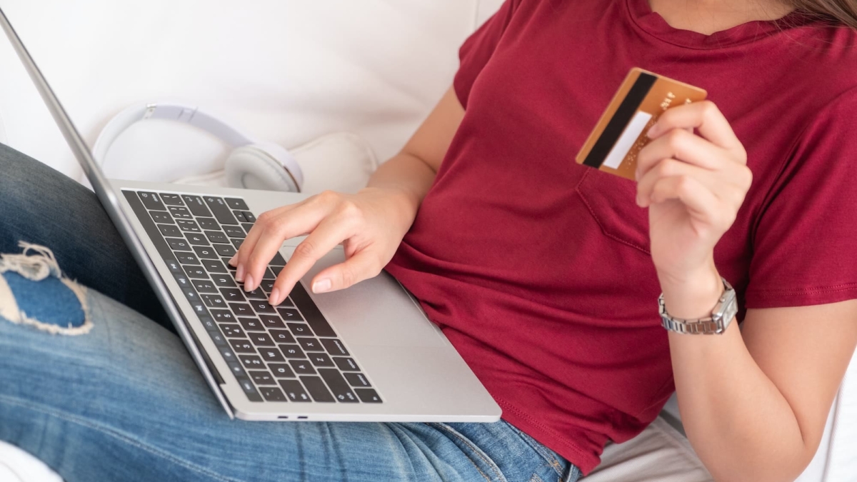 Close up woman holding credit card and use laptop shopping online on sofa